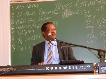 As seen on the board, various features of the blues are demonstrated on the piano.
